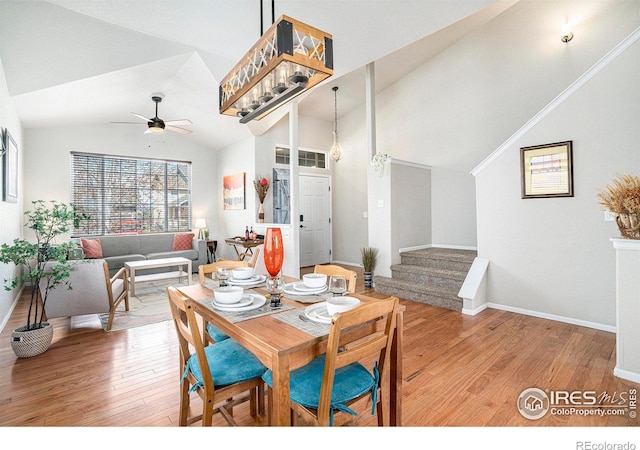 dining space with stairway, ceiling fan, vaulted ceiling, and hardwood / wood-style floors