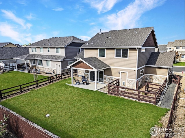 rear view of house with a patio, a fenced backyard, and stone siding