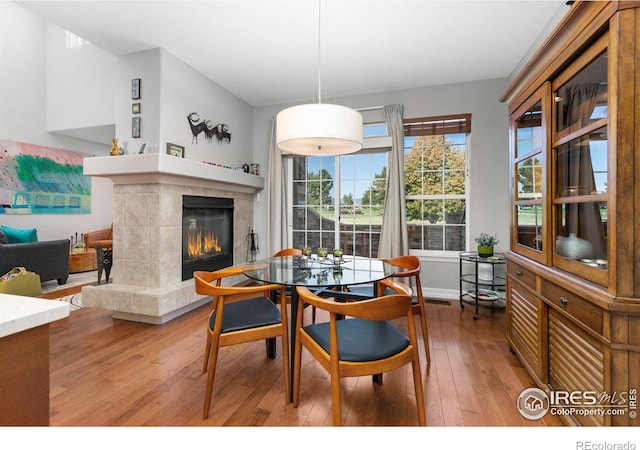 dining area with a tiled fireplace and hardwood / wood-style flooring