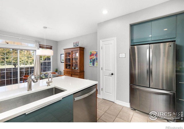 kitchen with stainless steel appliances, sink, light tile patterned floors, and decorative light fixtures