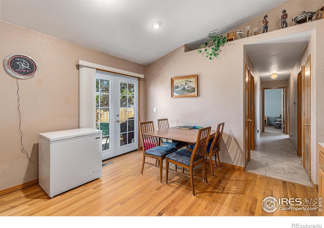 dining room with light hardwood / wood-style flooring, french doors, and vaulted ceiling