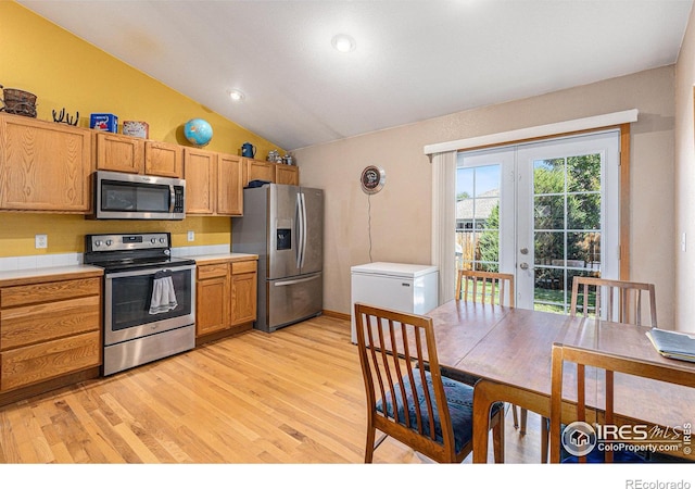 kitchen featuring french doors, vaulted ceiling, appliances with stainless steel finishes, and light hardwood / wood-style flooring