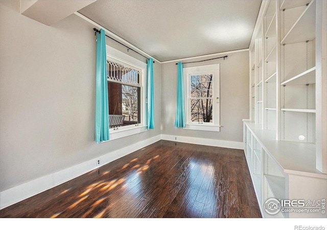 spare room featuring dark wood-type flooring and crown molding