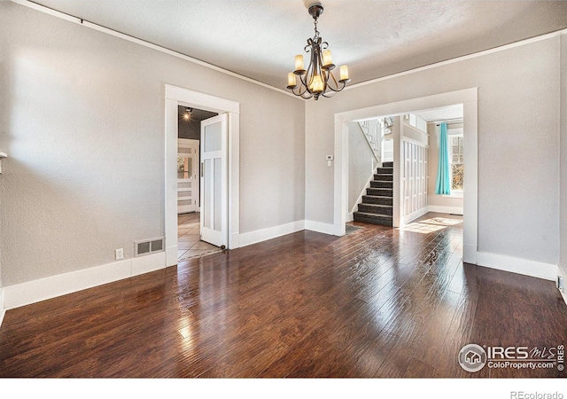 spare room with crown molding, hardwood / wood-style floors, and a notable chandelier