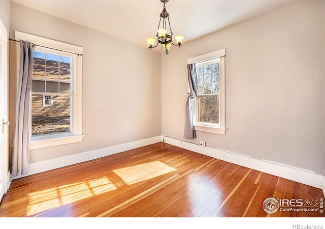 unfurnished room featuring an inviting chandelier and hardwood / wood-style flooring