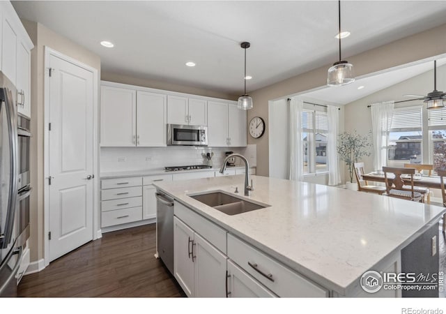 kitchen with an island with sink, appliances with stainless steel finishes, sink, and pendant lighting