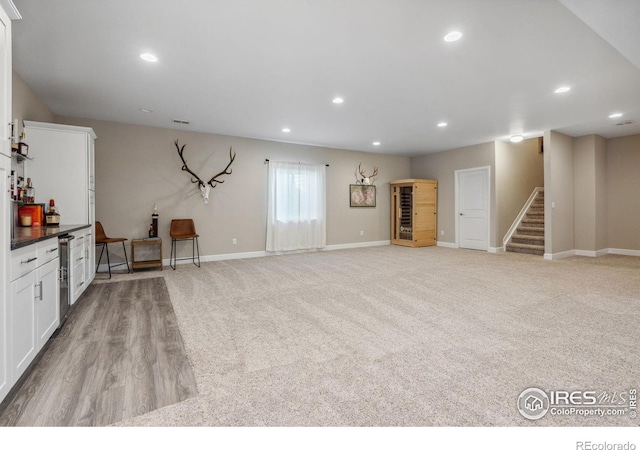 unfurnished living room with bar area and light carpet