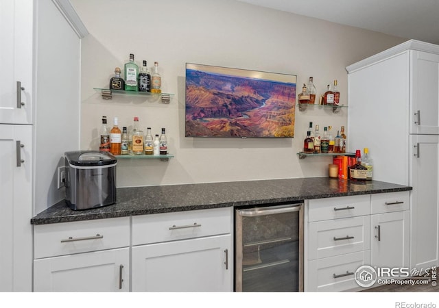 bar featuring wine cooler, dark stone counters, and white cabinets