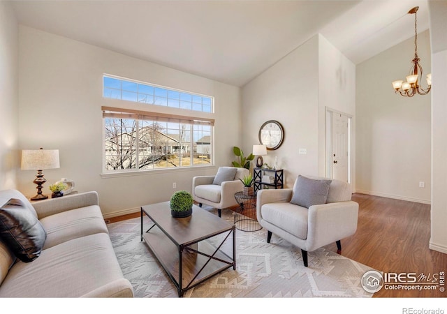 living area featuring high vaulted ceiling, a notable chandelier, baseboards, and wood finished floors