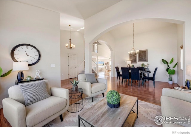 living room with wood finished floors, a towering ceiling, baseboards, and an inviting chandelier