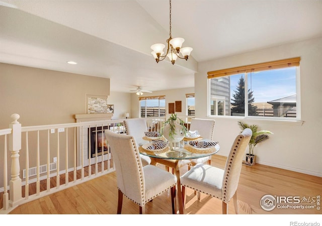 dining space featuring baseboards, vaulted ceiling, ceiling fan with notable chandelier, and light wood-style floors