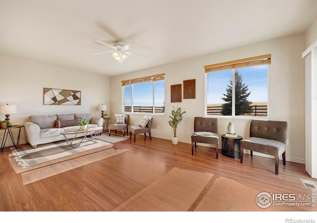 living room with a healthy amount of sunlight, a ceiling fan, visible vents, and wood finished floors