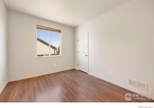 unfurnished room featuring visible vents, baseboards, and wood finished floors