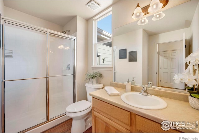 bathroom with toilet, a shower stall, visible vents, and vanity