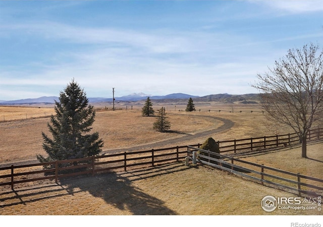 view of yard with a rural view, fence, and a mountain view