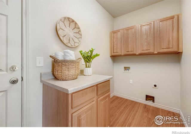 laundry area with cabinet space, baseboards, light wood-style flooring, hookup for a washing machine, and hookup for an electric dryer