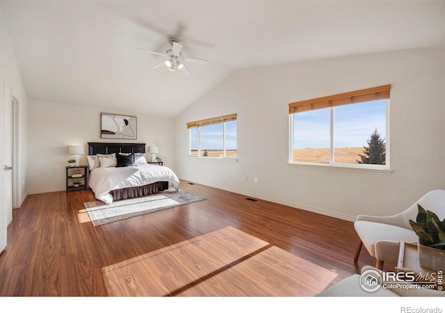 bedroom with vaulted ceiling, dark wood-type flooring, multiple windows, and baseboards