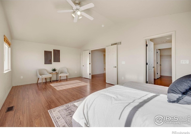 bedroom with lofted ceiling, visible vents, baseboards, and wood finished floors