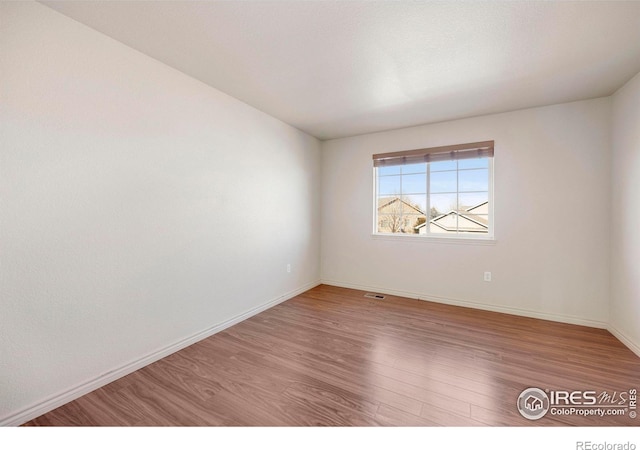 spare room with visible vents, baseboards, and wood finished floors