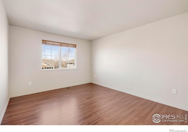 empty room featuring wood finished floors and baseboards