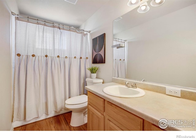 full bath with toilet, visible vents, wood finished floors, and vanity