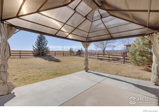 view of patio / terrace with a gazebo, a rural view, and fence