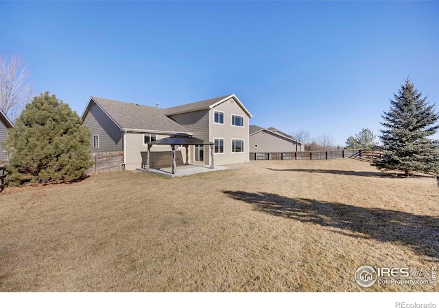 rear view of property featuring a patio area, a fenced backyard, a lawn, and a gazebo