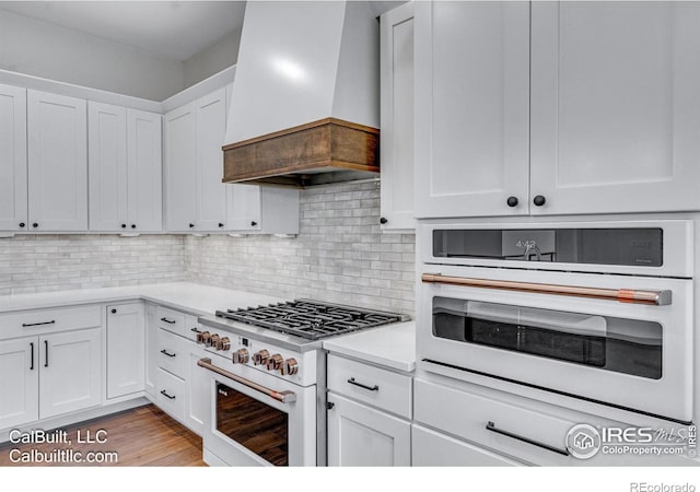 1233 Eliza Ave, Berthoud, CO 80513 - kitchen featuring white appliances, wall chimney range hood, white cabinetry, light countertops, and decorative backsplash