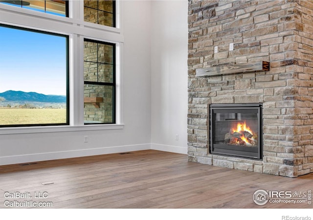 1233 Eliza Ave, Berthoud, CO 80513 - unfurnished living room featuring wood finished floors, a stone fireplace, and a mountain view
