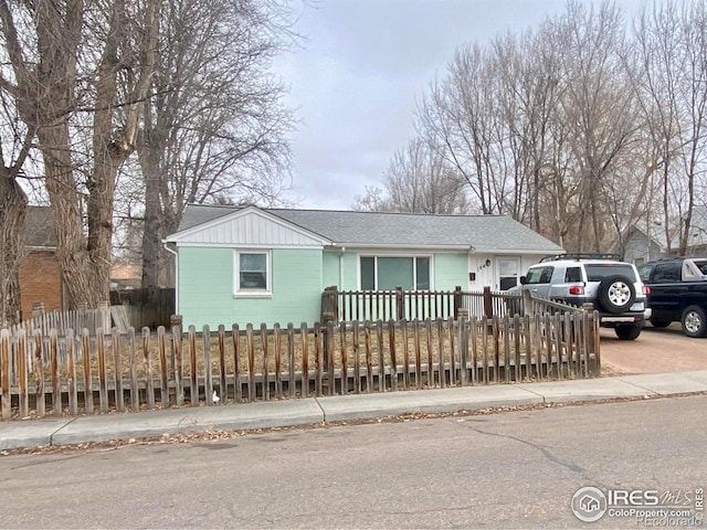 view of front of house with a fenced front yard, concrete driveway, and roof with shingles