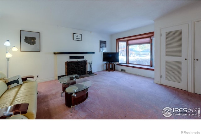 living room featuring a fireplace with flush hearth, baseboards, visible vents, and carpet