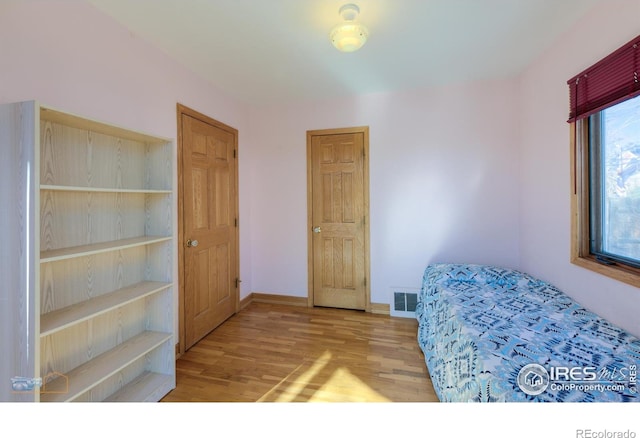 unfurnished bedroom featuring baseboards, wood finished floors, and visible vents