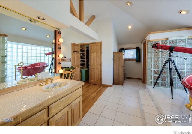 full bath with a freestanding tub, vaulted ceiling, vanity, and recessed lighting