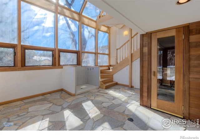 spare room featuring baseboards, stone finish floor, and stairs