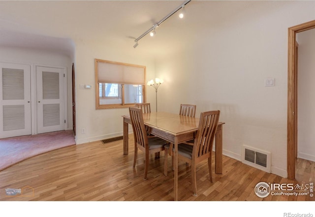 dining area featuring track lighting, light wood-type flooring, visible vents, and baseboards