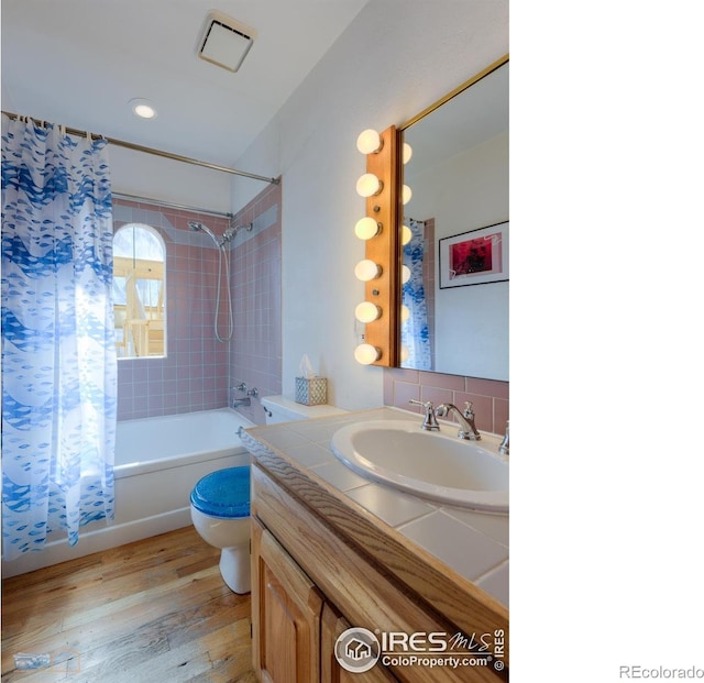 bathroom with wood finished floors, visible vents, toilet, vanity, and shower / tub combo with curtain
