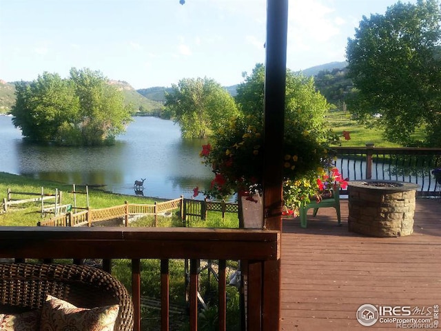 wooden terrace featuring a water view and an outdoor fire pit