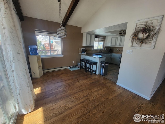 kitchen with a breakfast bar area, white cabinetry, vaulted ceiling with beams, hanging light fixtures, and a baseboard radiator