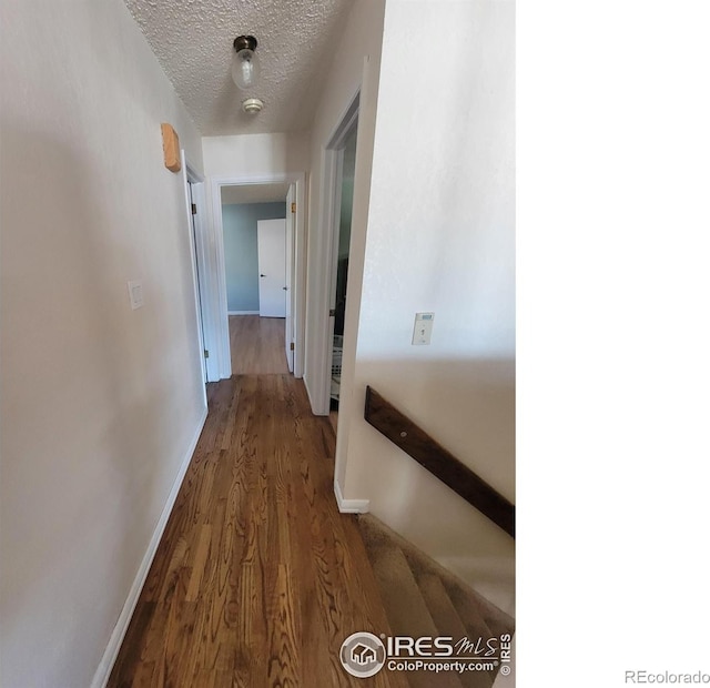 hallway with dark hardwood / wood-style flooring and a textured ceiling