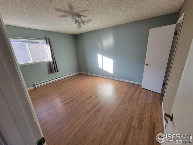 spare room featuring a baseboard heating unit, a textured ceiling, ceiling fan, and light hardwood / wood-style flooring