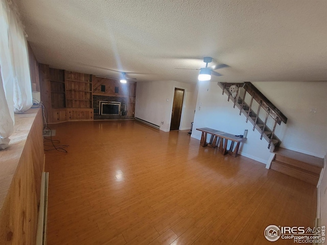 unfurnished living room with ceiling fan, hardwood / wood-style floors, built in features, and a textured ceiling