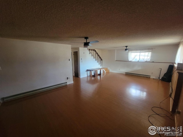 additional living space with a baseboard heating unit, a textured ceiling, wood-type flooring, and ceiling fan