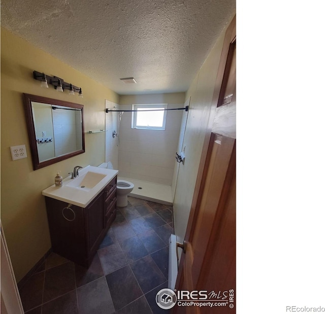 bathroom with a tile shower, a baseboard radiator, vanity, toilet, and a textured ceiling