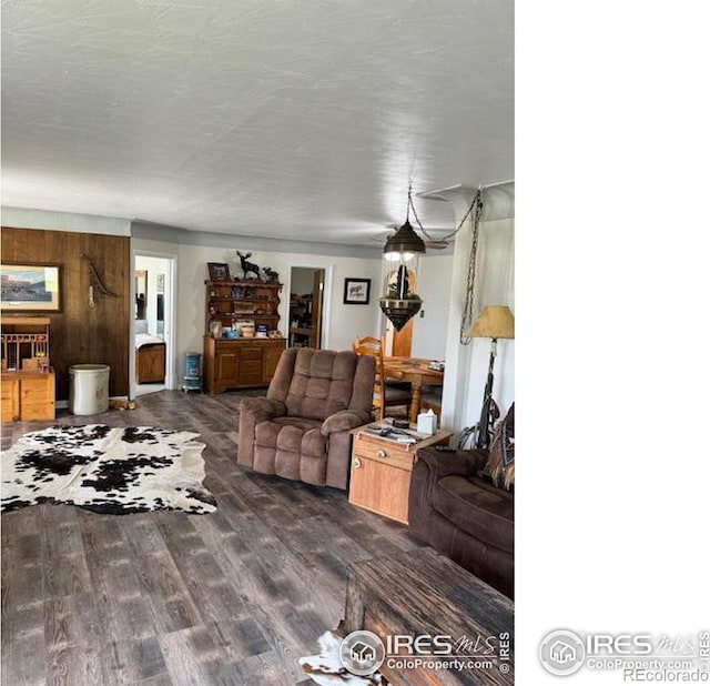 living room featuring dark hardwood / wood-style floors, a textured ceiling, and wood walls