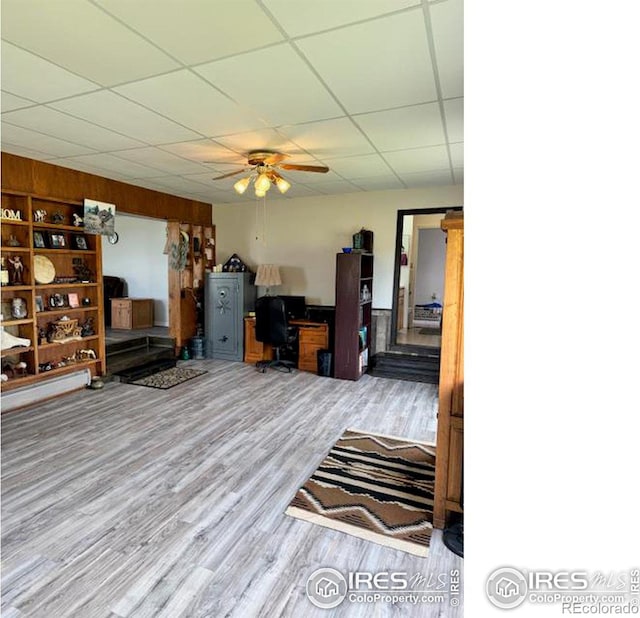 living room with hardwood / wood-style flooring, a paneled ceiling, and ceiling fan