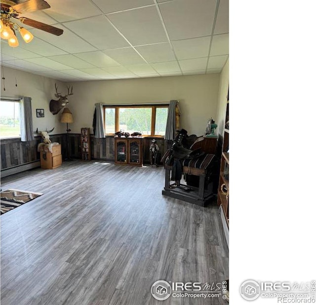 living room featuring hardwood / wood-style flooring, a healthy amount of sunlight, a baseboard heating unit, and a drop ceiling