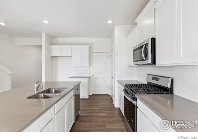 kitchen featuring sink, appliances with stainless steel finishes, dark hardwood / wood-style floors, white cabinets, and backsplash