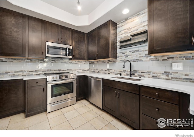 kitchen with tasteful backsplash, stainless steel appliances, dark brown cabinets, light countertops, and a sink