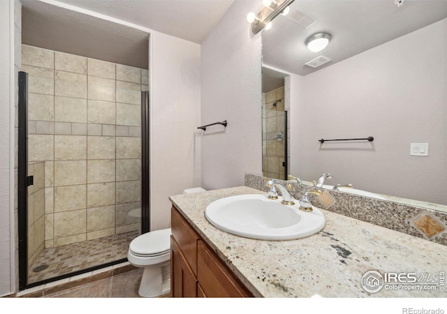 full bathroom featuring toilet, a stall shower, visible vents, and vanity