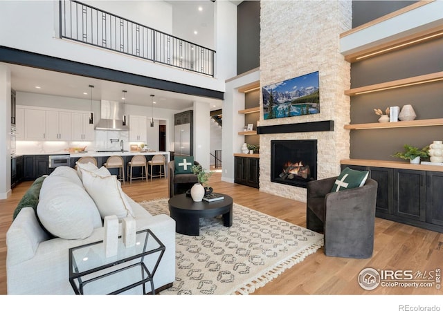 3650 Tall Grass Ct, Timnath, CO 80547 - living area with light wood finished floors, a stone fireplace, a towering ceiling, and built in shelves